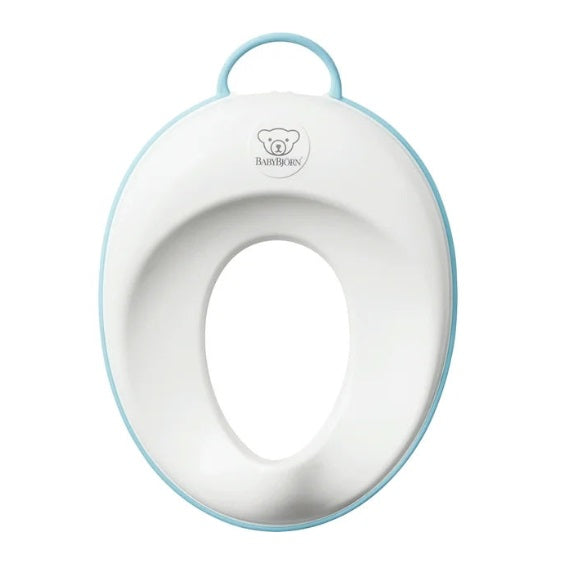 BabyBjörn Toilet Trainer in white with a light blue rim, built-in handle, and BABY BJÖRN logo.