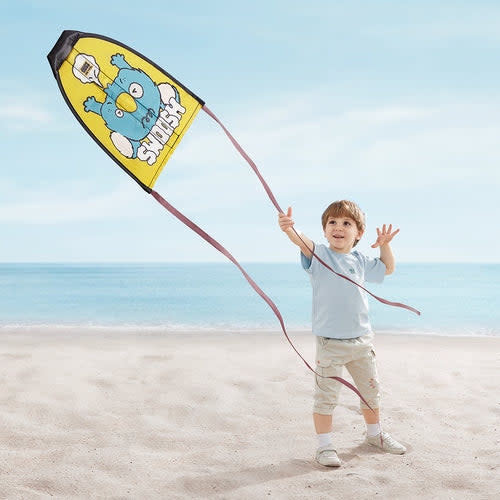BC Babycare Kite Launcher Toy yellow; child on the beach flying a yellow kite with a blue character