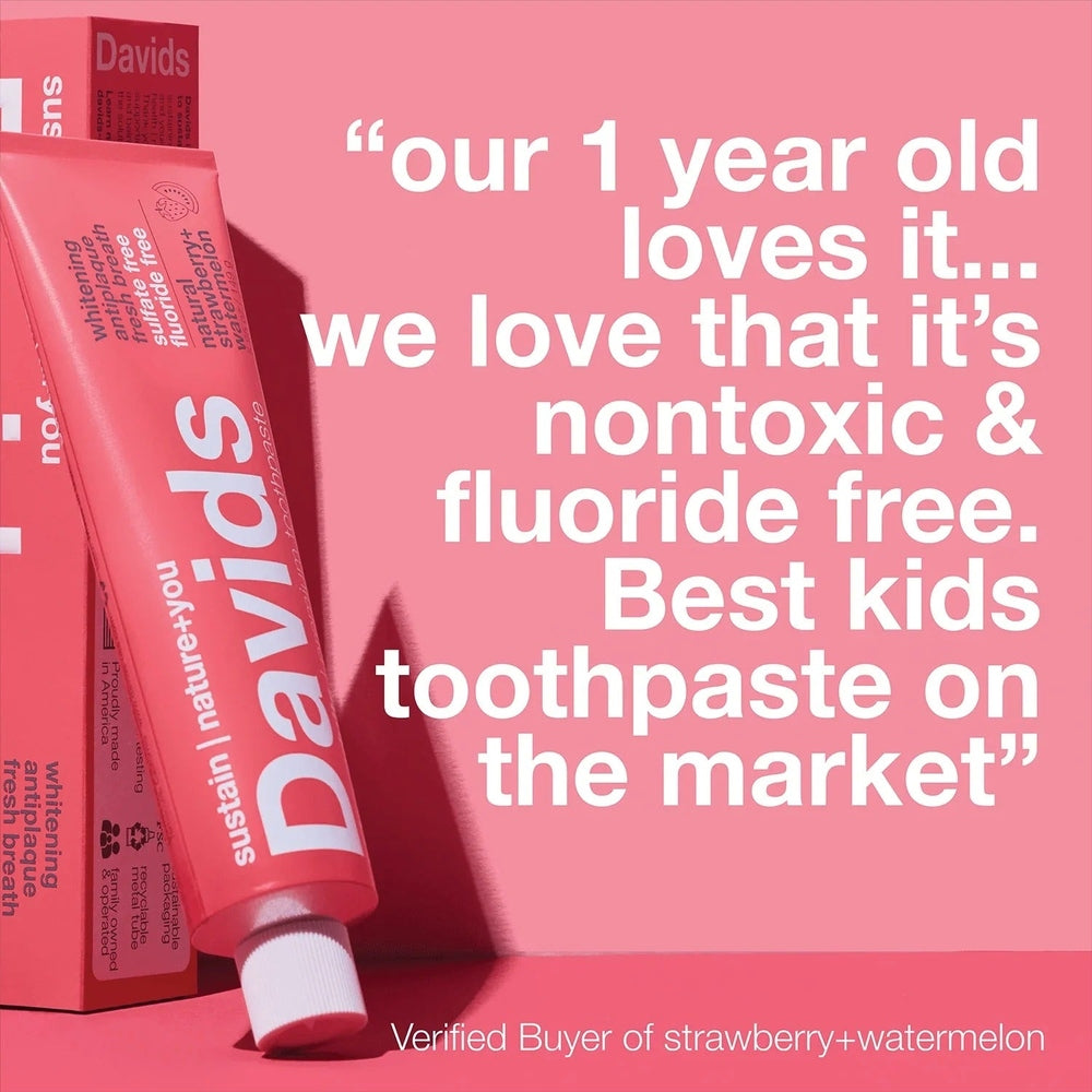 Davids Toothpaste Fluoride Free Strawberry Watermelon rests beside its pink box on a pink backdrop, highlighting the fluoride-free strawberry-watermelon flavor.