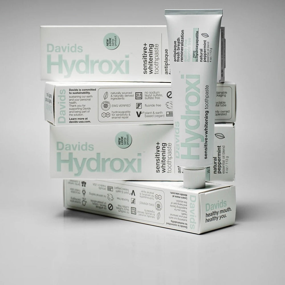 Davids Toothpaste Sensitive & Whitening Fluoride Free Peppermint tube standing beside stacked boxes