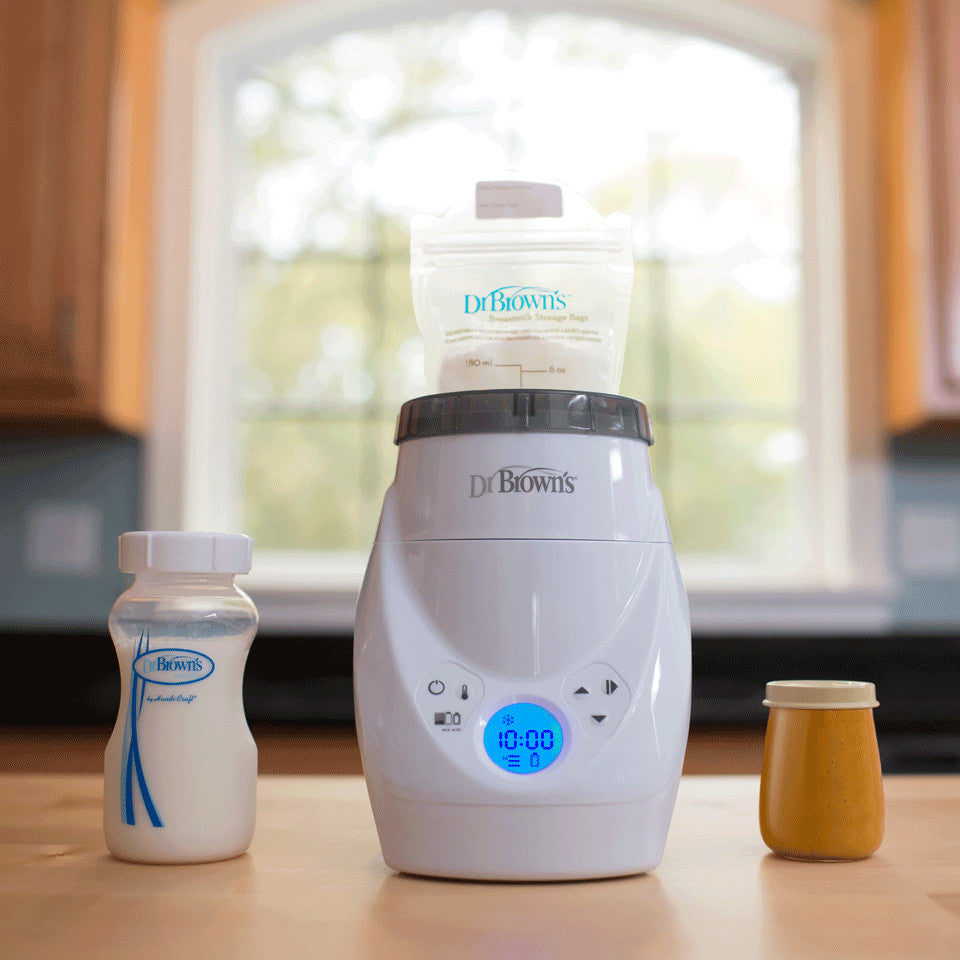 Dr. Brown's MilkSpa bottle warmer with blue digital display; bottle and jar on a kitchen counter.