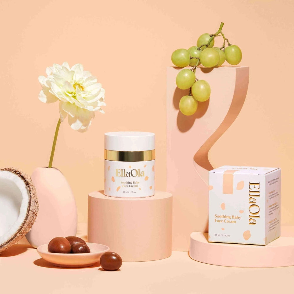 EllaOla Fragrance Free Moisturizing Baby Face Cream 50ml on a pink pedestal beside its decorative box.