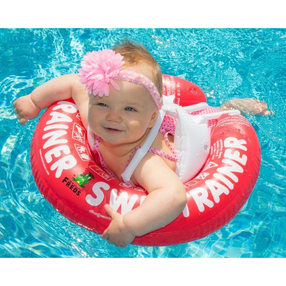FREDS Swimtrainer Classic Red 3M-4Y baby float in pool with pink flower headband