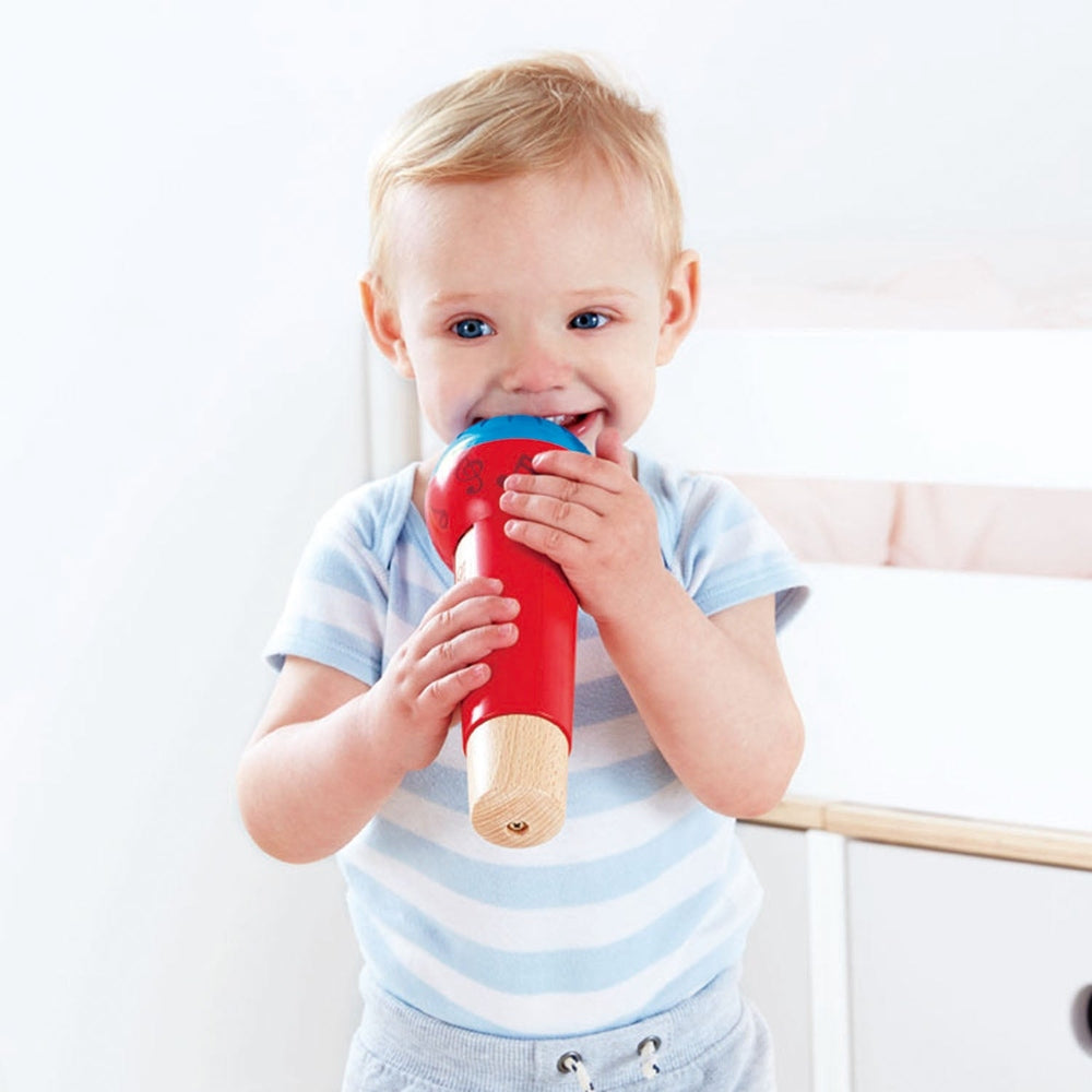 Hape Mighty Echo Microphone in red with blue mouthpiece, wooden tip, being held by a smiling toddler.