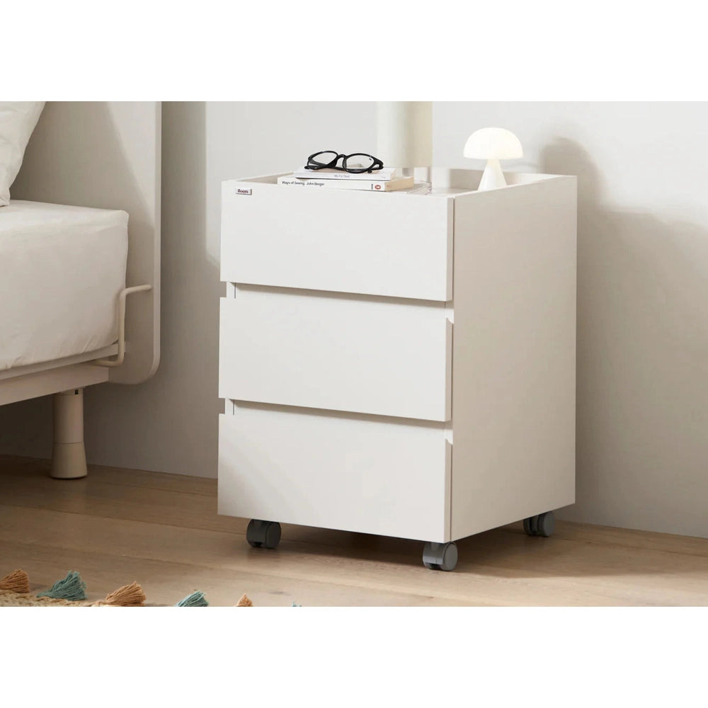 Iloom Roy Mono Desk Drawer white mobile storage cabinet on caster wheels beside a bed