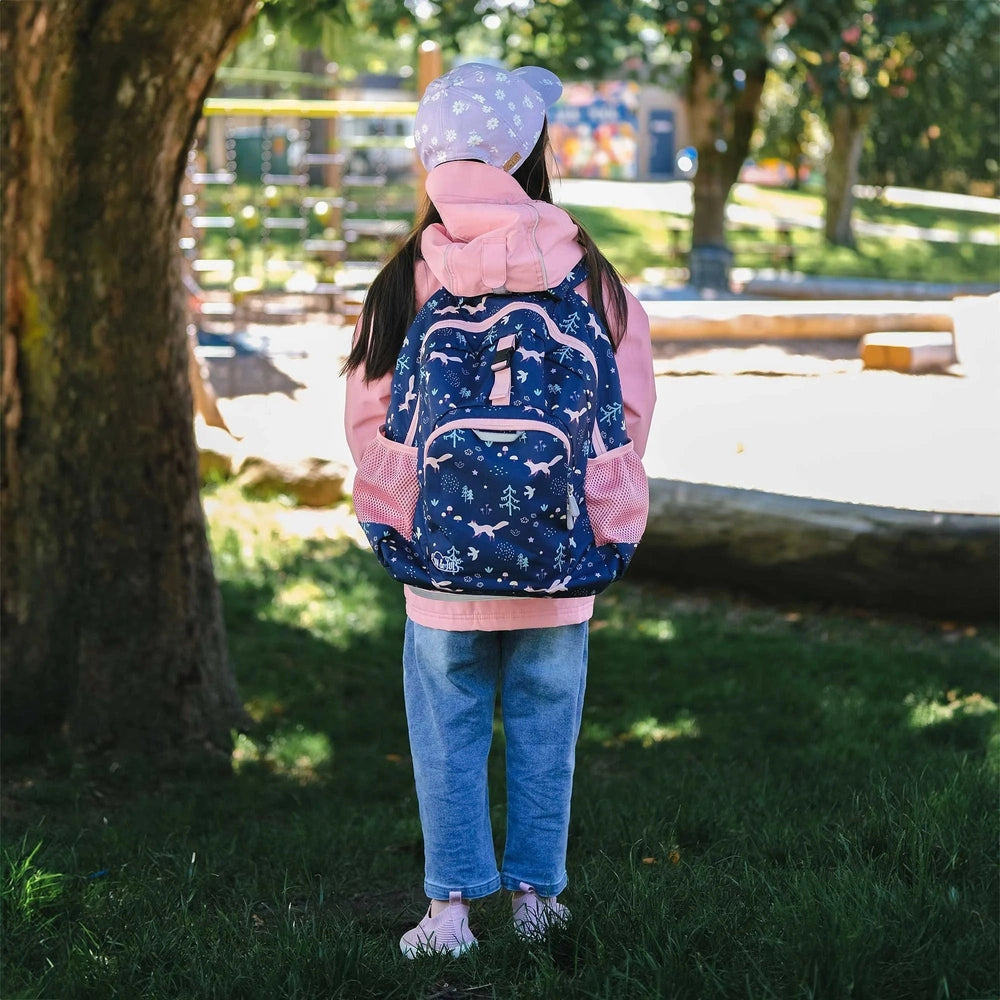 Jan & Jul Kids Backpack in navy with pink accents on a child in a pink hoodie outdoors, showing pink mesh side pockets.