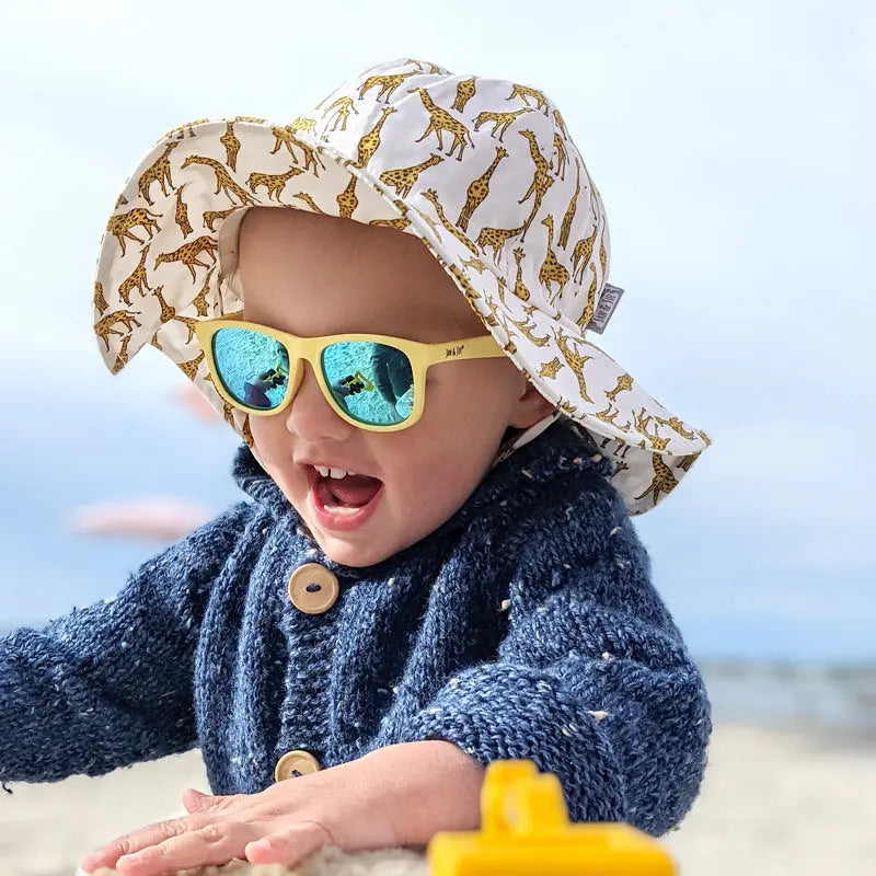 JAN & JUL Kids Cotton Floppy Hat Giraffe; baby at the beach wears its wide brim for sun protection.