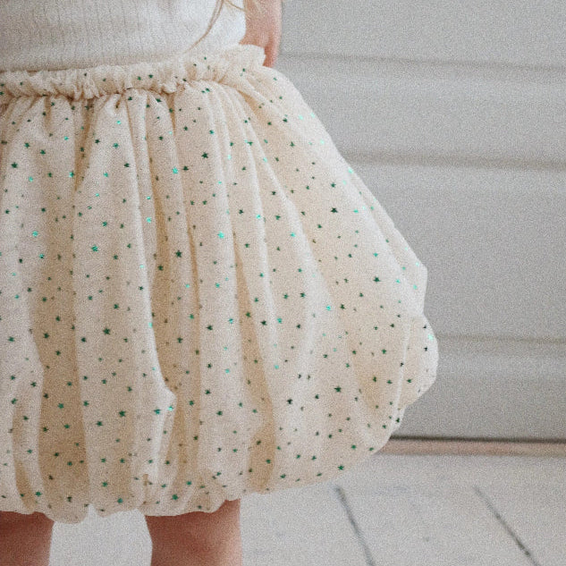 Konges Slojd Fairy Balloon Skirt Fairy Etoile Green worn by toddler, cream fabric with tiny green stars.