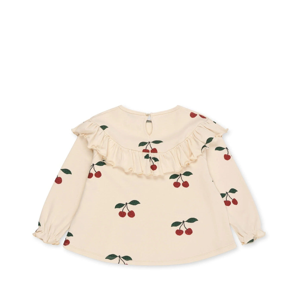 Konges Slojd Malli Glitter Blouse in cream with cherry print, ruffled yoke, and elastic-cuffed long sleeves.