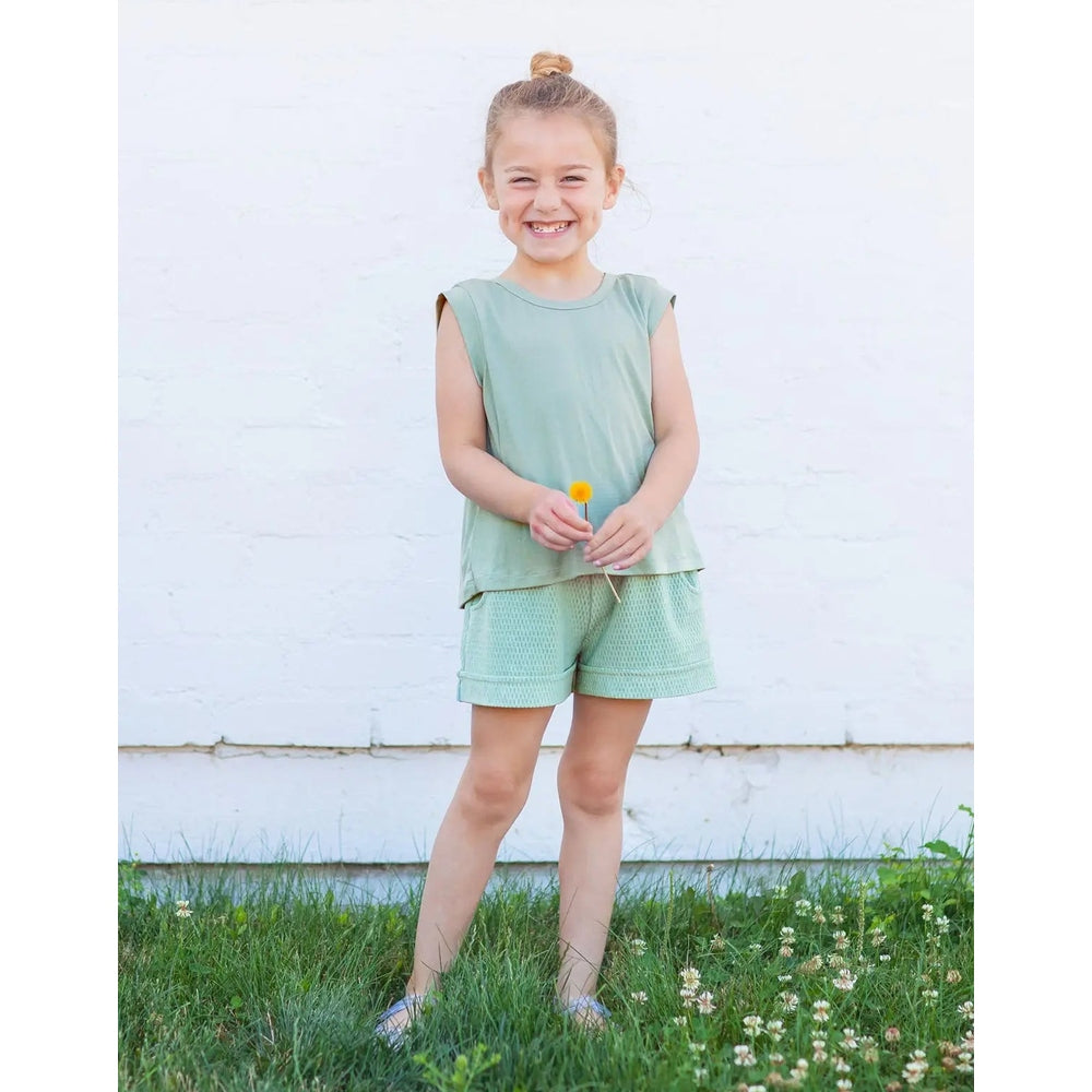Mabel and Honey Sydney textured knit 2pc set in green; girl stands in grass holding a yellow flower.