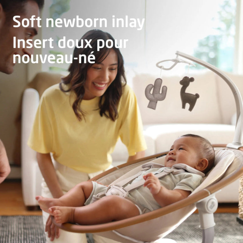 Maxi-Cosi Cassia Swing in beige seat, soothing motion as mom watches baby under overhead toy bar.