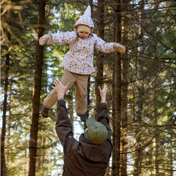 Mini A Ture Matwang Fleece Lined Winter Jacket being lifted by an adult in a sunlit forest, cozy outdoor play.