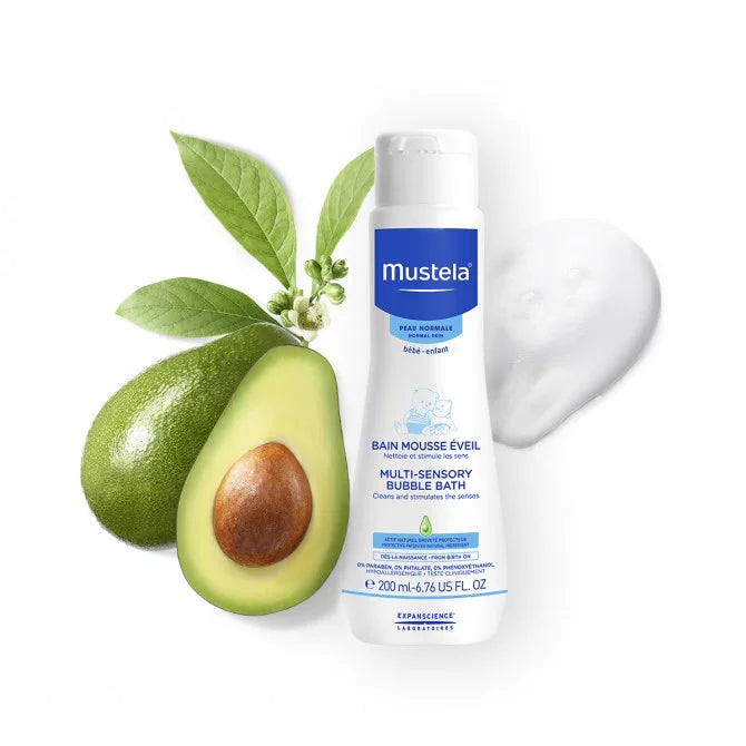 Mustela Multi-Sensory Bubble Bath With Avocado 200 ml, white bottle beside avocado and leaves with foam.