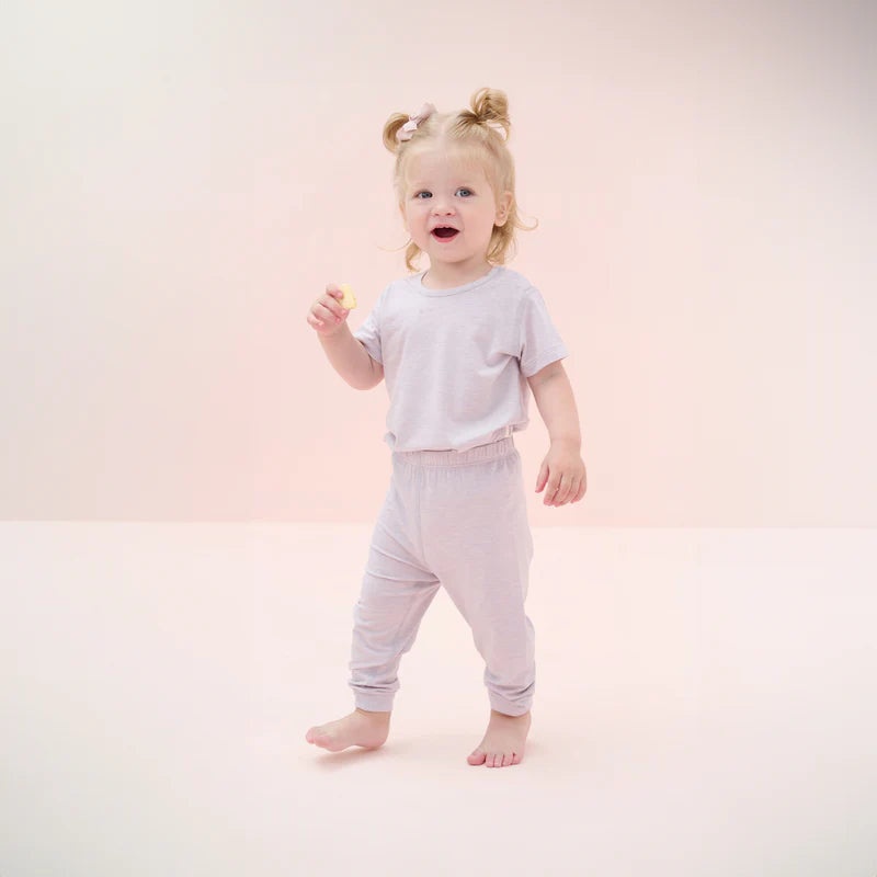 Nest Designs Bamboo Jersey Short Sleeve Pj Set Lavender Blue worn by a barefoot, smiling toddler girl in lavender pajamas.