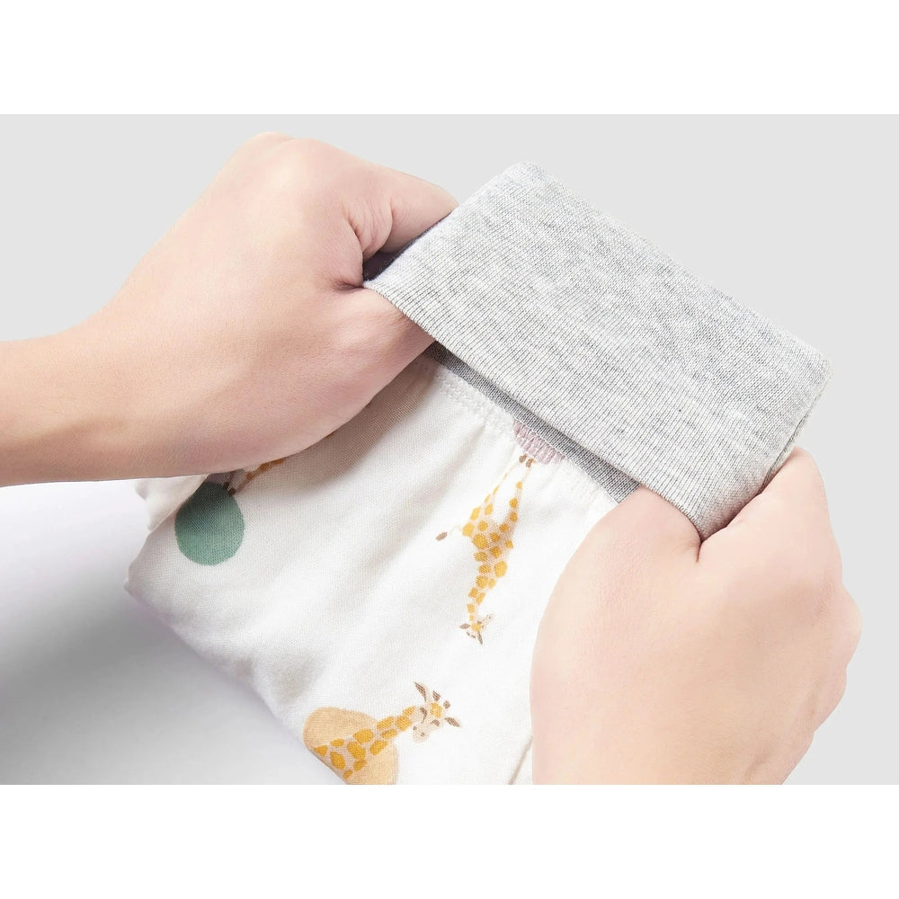 Nest Designs bamboo long-sleeve footed sleep bag 1.0 TOG in white giraffe print, being adjusted at the grey cuff.
