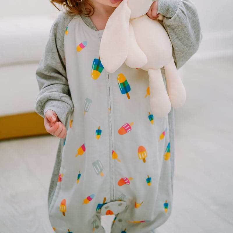 Nest Designs bamboo long-sleeve, footed sleep bag in pale gray with colorful popsicle print, toddler wearing.