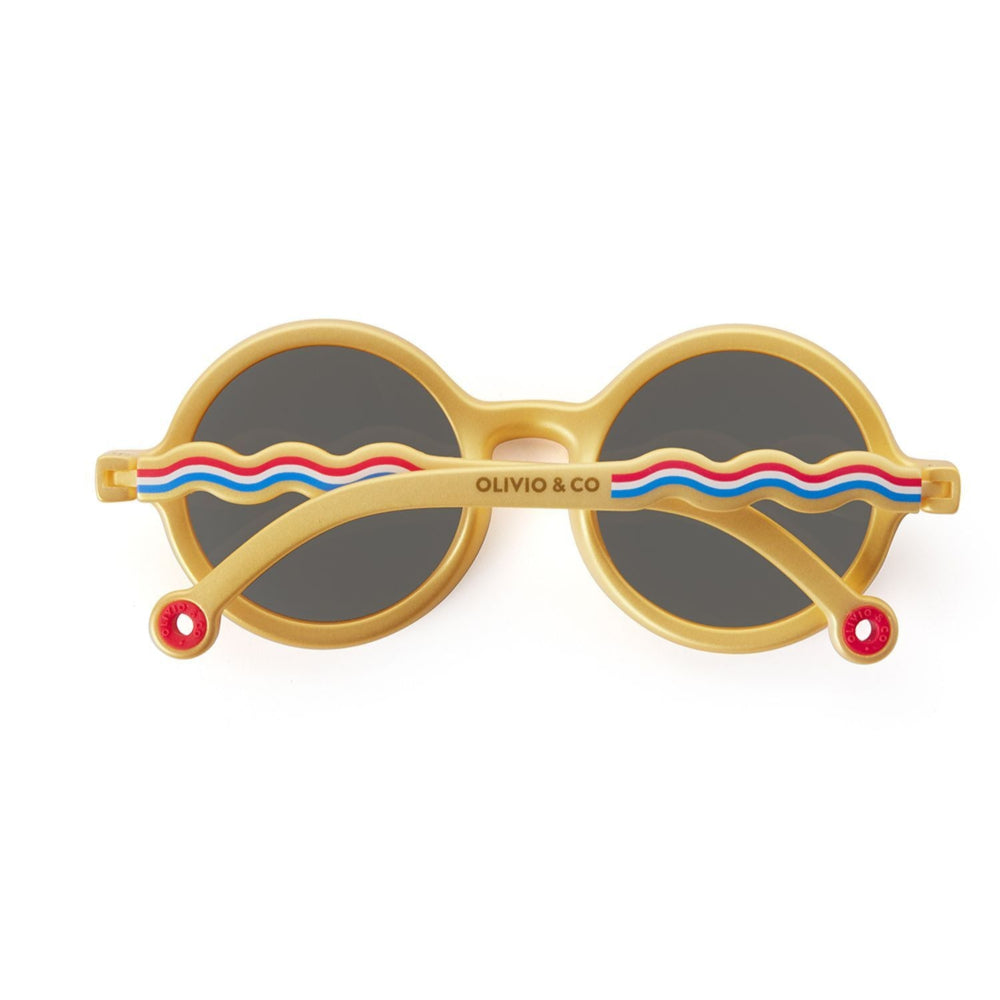 Olivio & Co Round Sunglasses Kids/Junior Classic Olivio Medallion Gold sunglasses, gold frames and dark lenses resting on white surface
