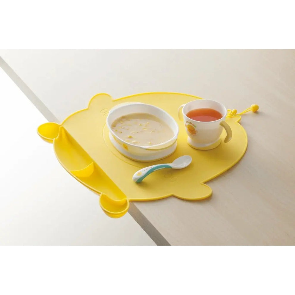 Piyo Piyo Foodie Silicone Placemat Yellow, flower-shaped with bowl, cup and spoon during baby feeding.