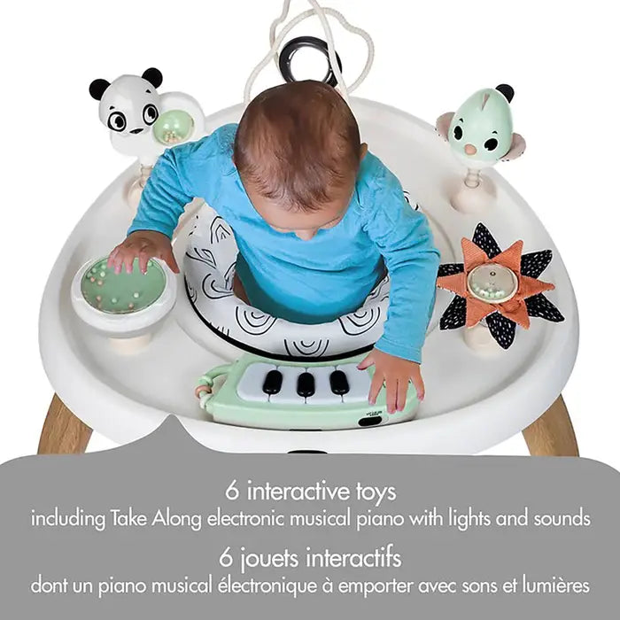 Tiny Love 5-In-1 Here I Grow stationary activity center; baby in blue sits, taps piano keys, toys swing above.