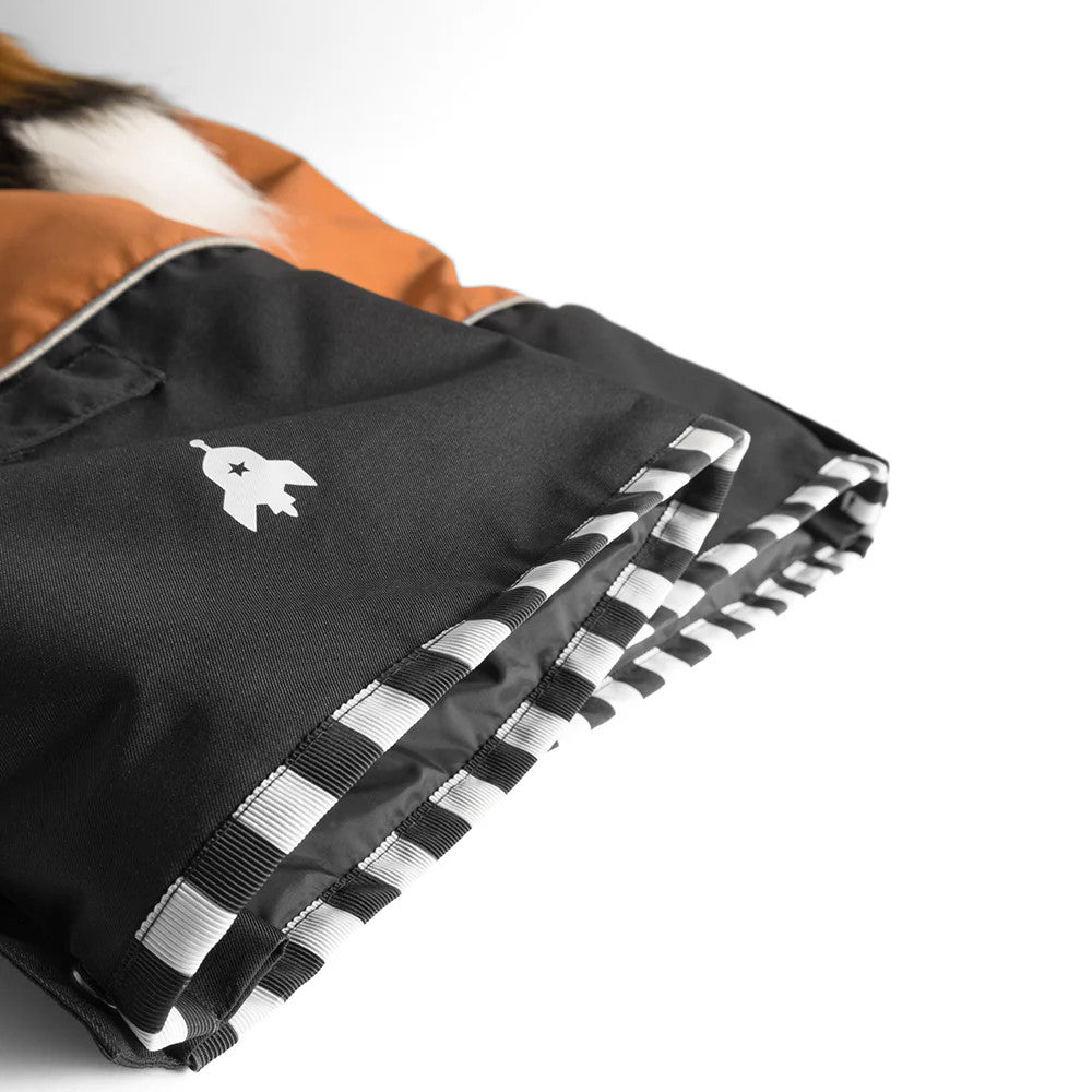 Weedo Foxdo Fox Gold Brown Snowsuit in black with orange hood; striped cuffs folded at the sleeve.