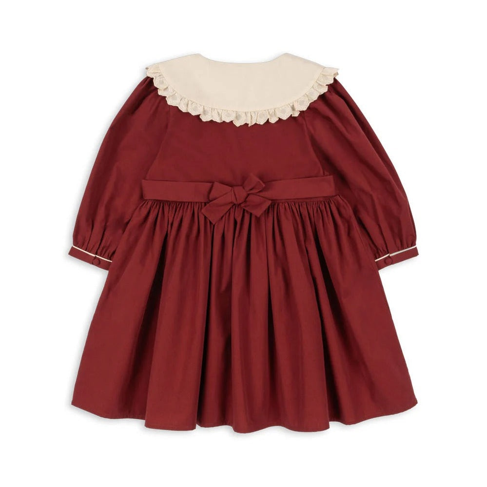 Konges Slojd Coeur Dress Red Dahlia: burgundy baby dress with cream lace collar and waist bow, laid flat.