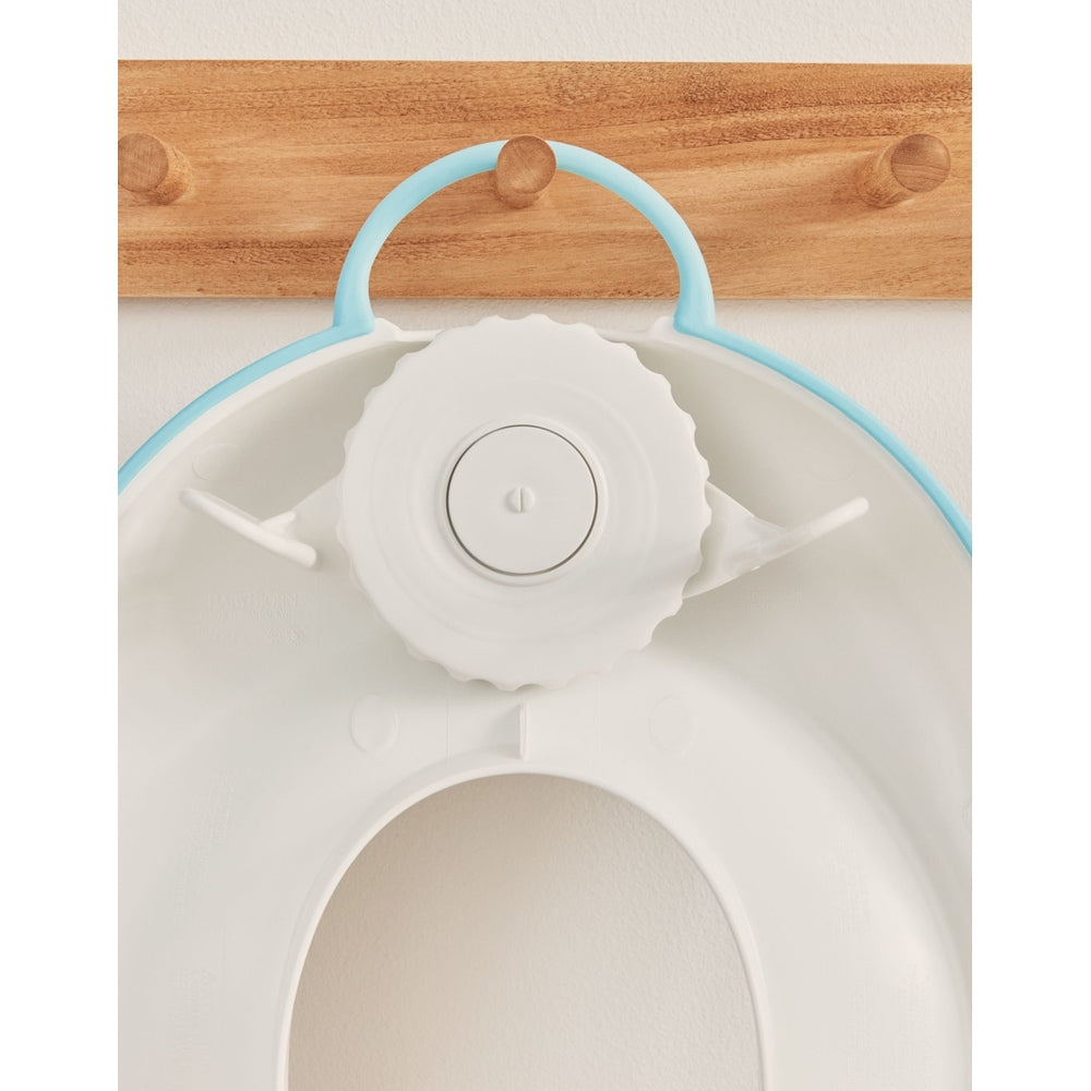 Baby Björn Toilet Trainer, white with light-blue rim, showing the central locking dial securing the seat.