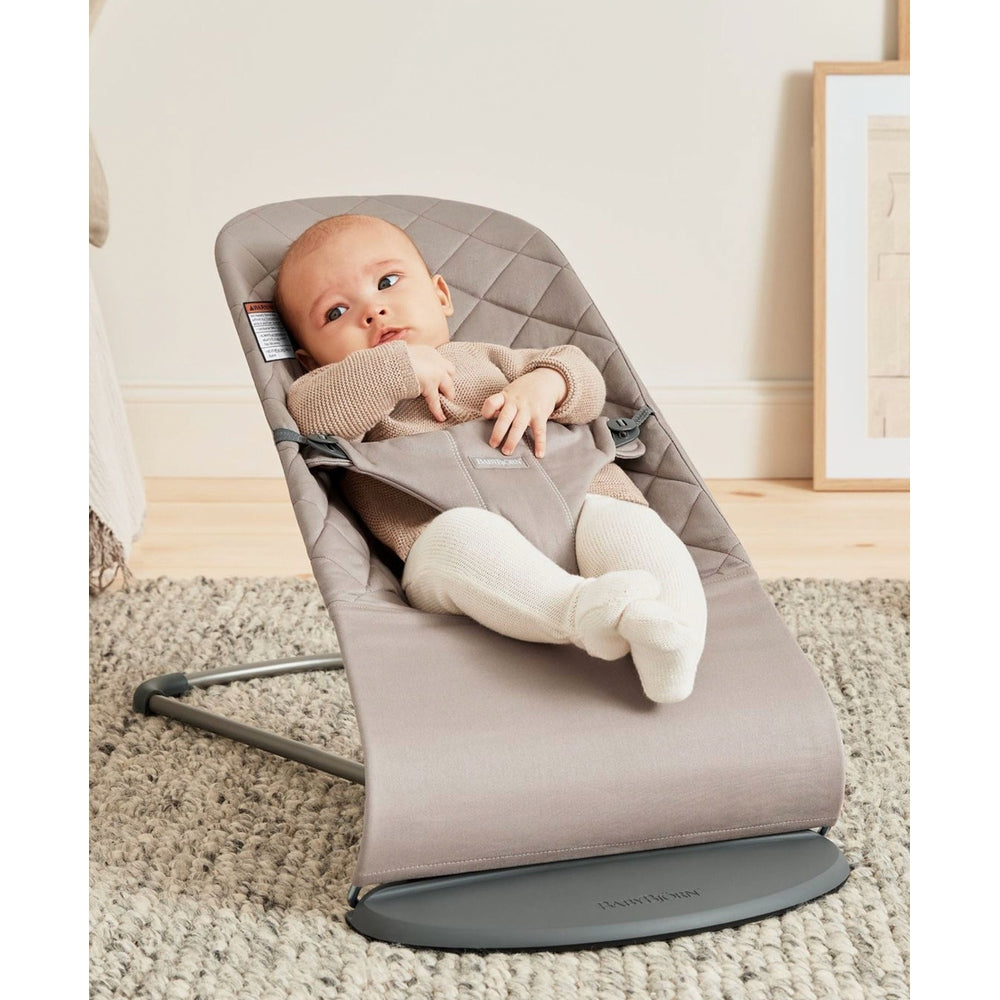 BabyBjörn Bouncer Bliss in gray fabric, baby lounging securely in the reclined seat on a sturdy base.