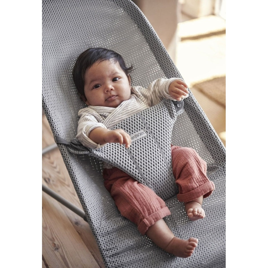 BabyBjörn Bouncer Bliss in grey mesh; baby sits securely in the supportive harness while lounging.