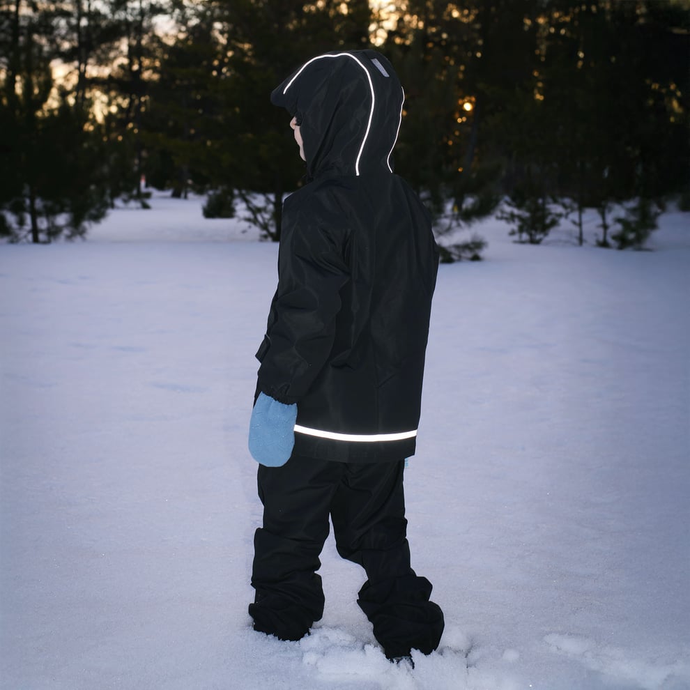 Jan & Jul Waterproof Cozy Dry Rain Jacket Navy Fox worn by child in snowy field, hood up, reflective trim.