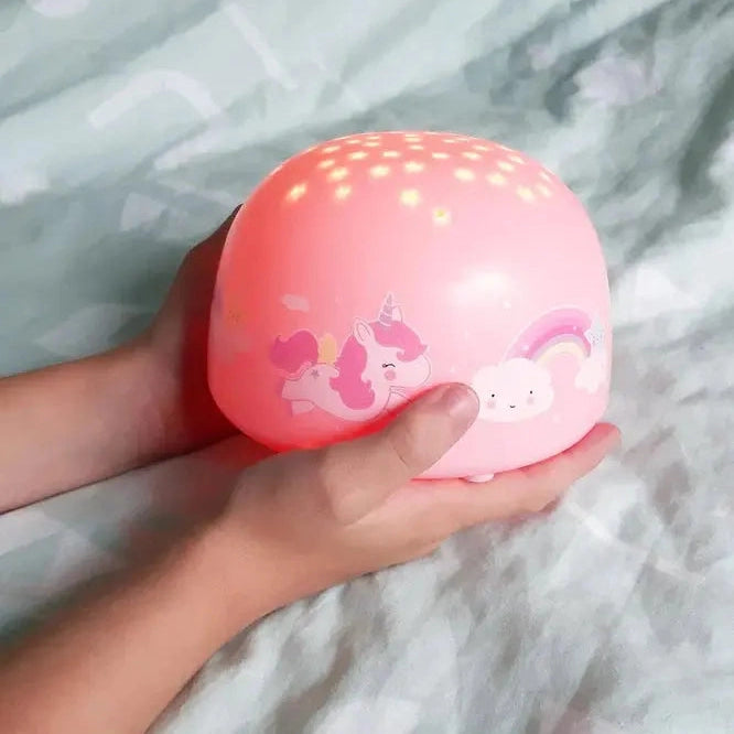 A Little Lovely Company Projector Night Light, pink sphere held by a child, projecting warm dot lights with unicorns and a rainbow.
