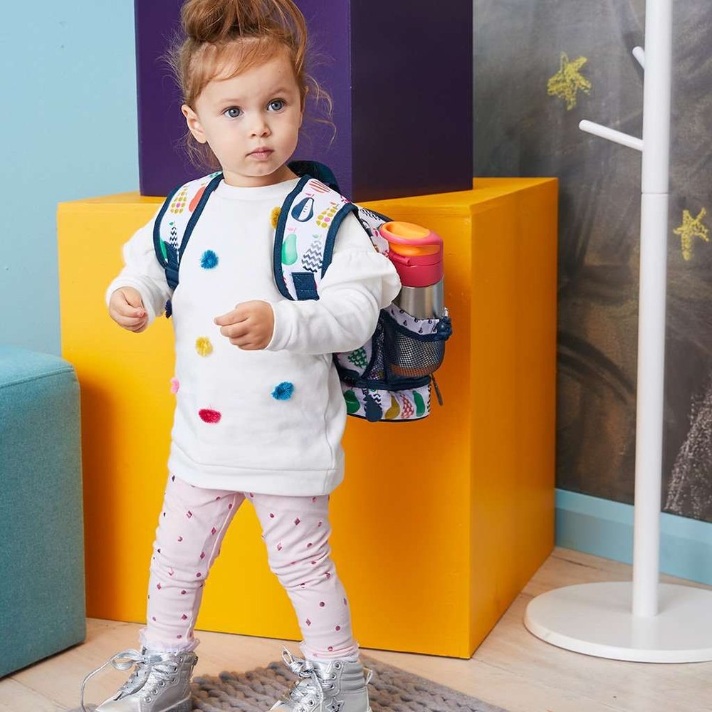 B.Box Insulated Bottle with pink lid and silver body on a colorful kid-friendly backpack