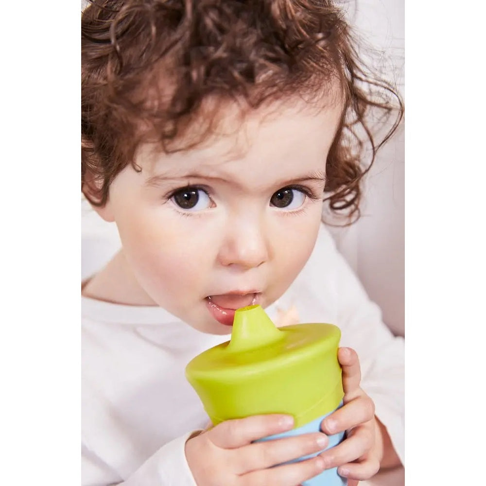 B.Box Silicone Lids Travel Pack baby sippy cup with bright green lid; child sips from it.