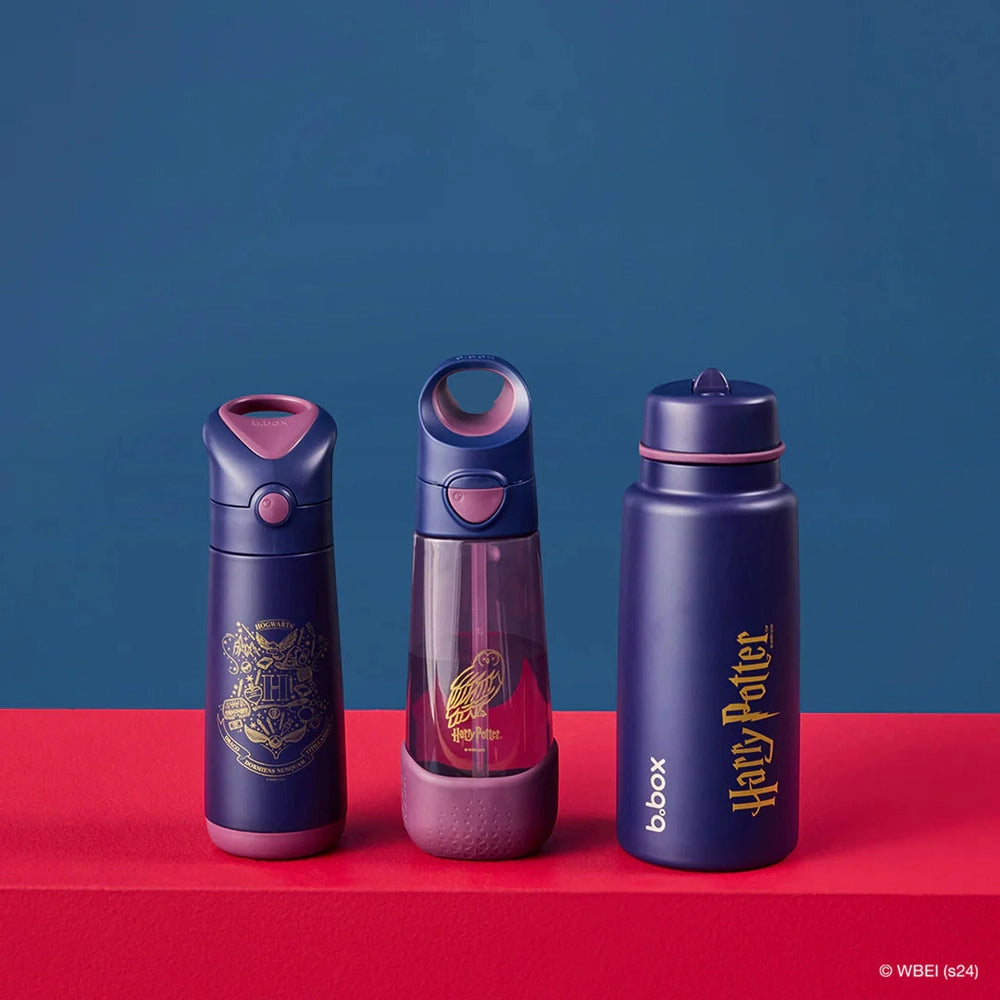 Three B.box Insulated Flip Top 1L water bottles in navy with pink accents stand upright on a red surface, one with Harry Potter design.