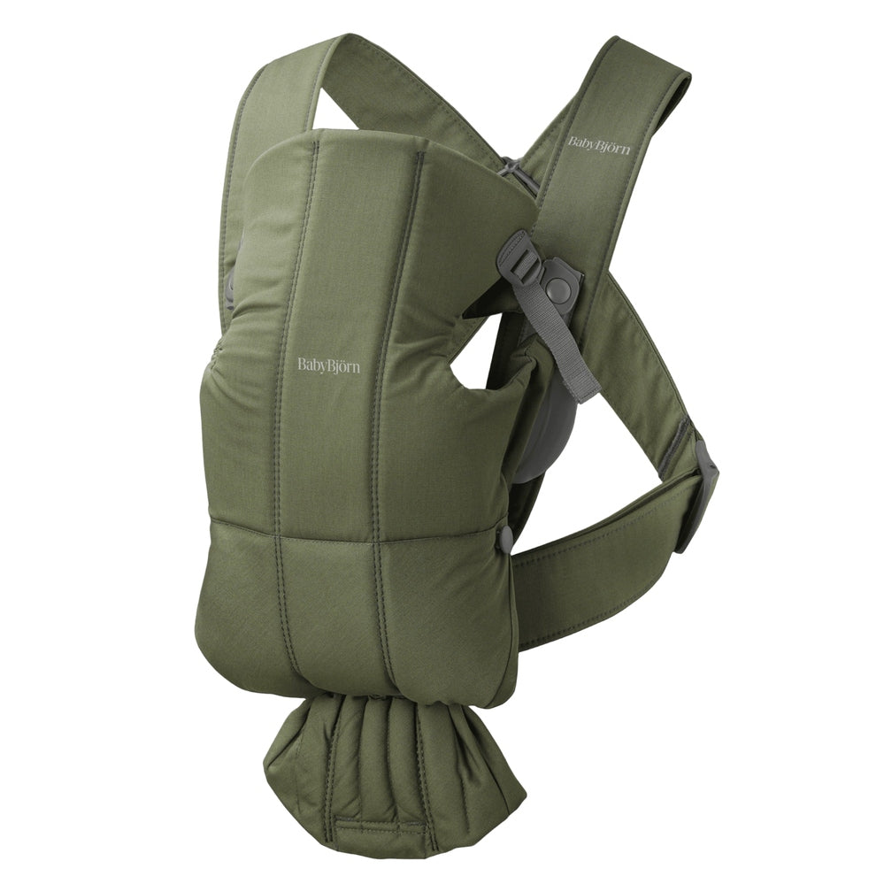 BabyBjörn Baby Carrier Mini worn by a parent, olive-green soft-structured carrier with padded straps and waist belt.