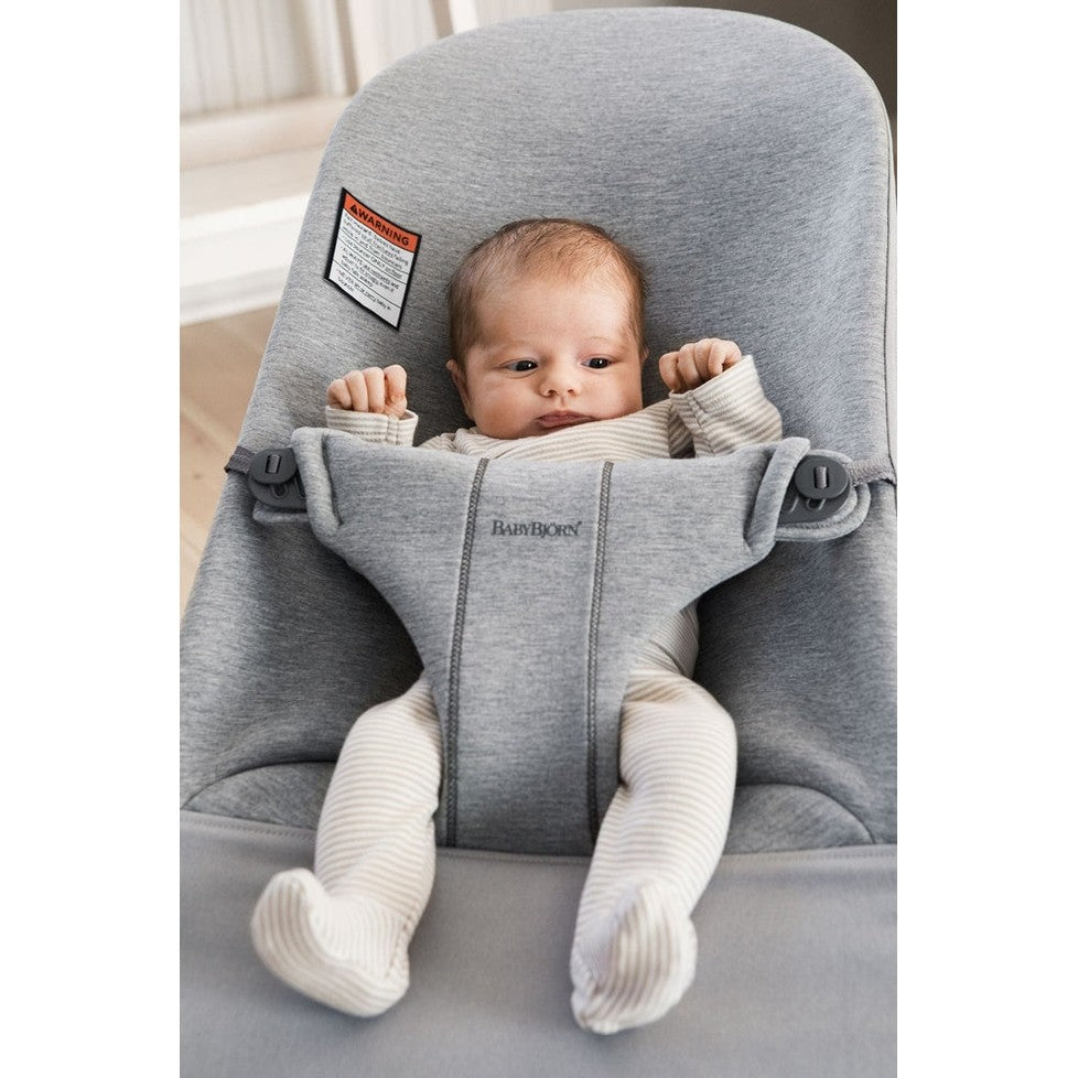 BABYBJÖRN Bouncer Bliss in gray with padded sides and secure harness as a baby sits upright with arms raised.