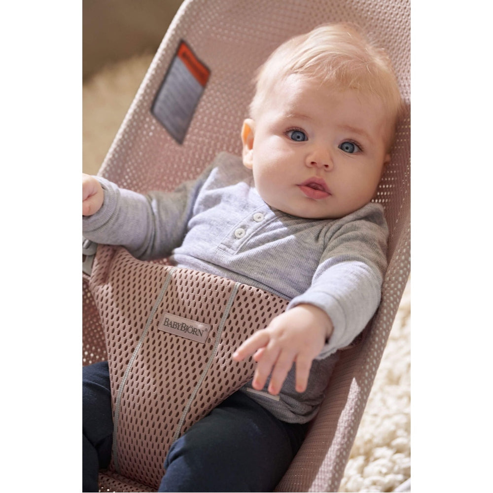 BabyBjörn Bouncer Bliss in soft pink mesh, BABY BJÖRN, with baby seated and reaching forward.