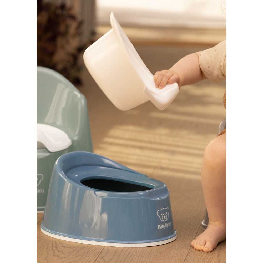 BabyBjörn Smart Potty blue with a white removable bowl; toddler places the bowl into the potty.