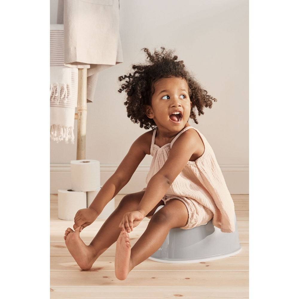 BabyBjörn Smart Potty in gray, with a joyful toddler seated on it in a soft neutral nursery.