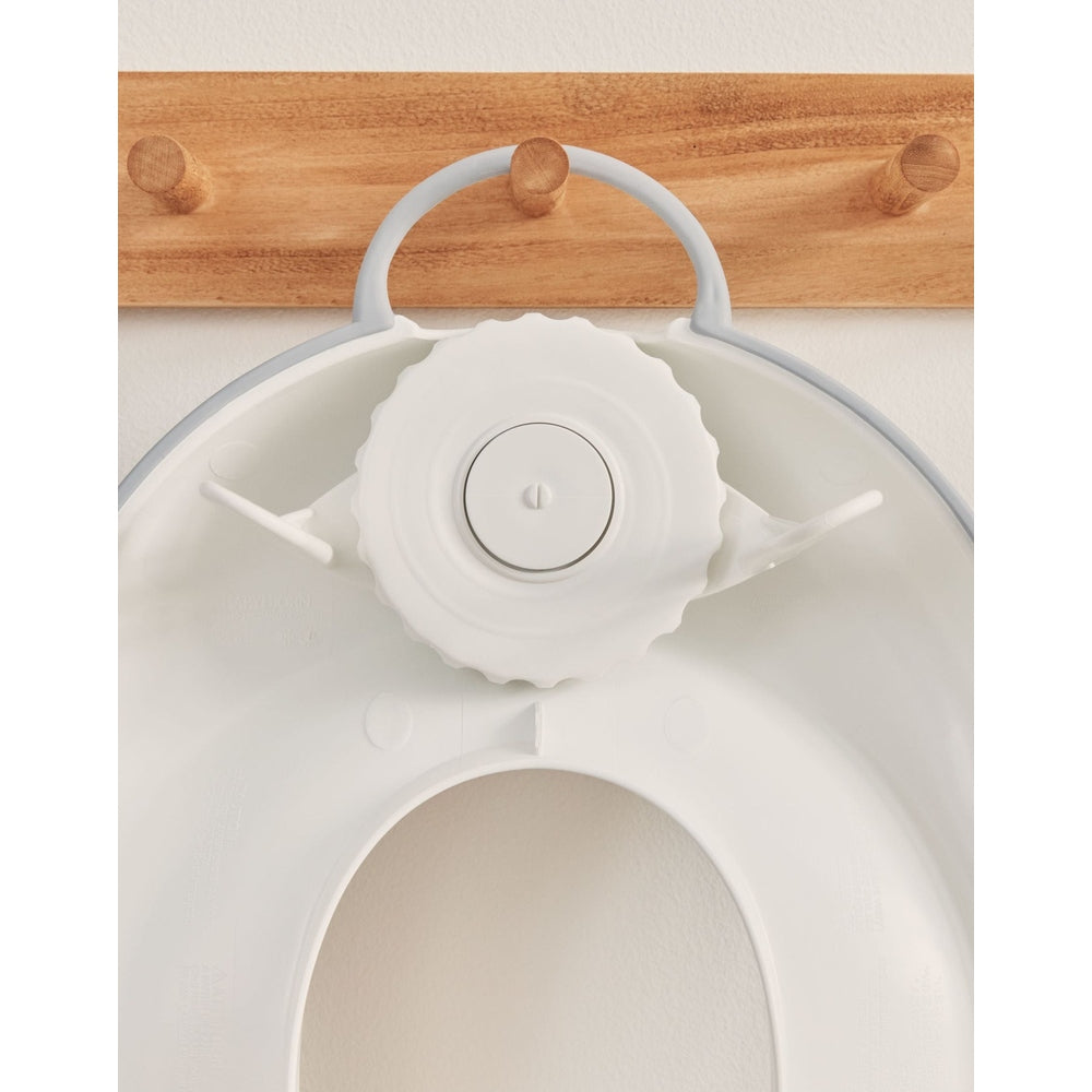 BABY BJÖRN Toilet Trainer white with adjustable dial, shown fitted to a toilet seat for secure training.