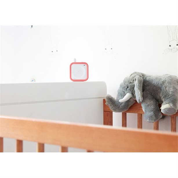 Beaba Minicall Audio Baby Monitor Coral on white crib with a gray plush elephant.