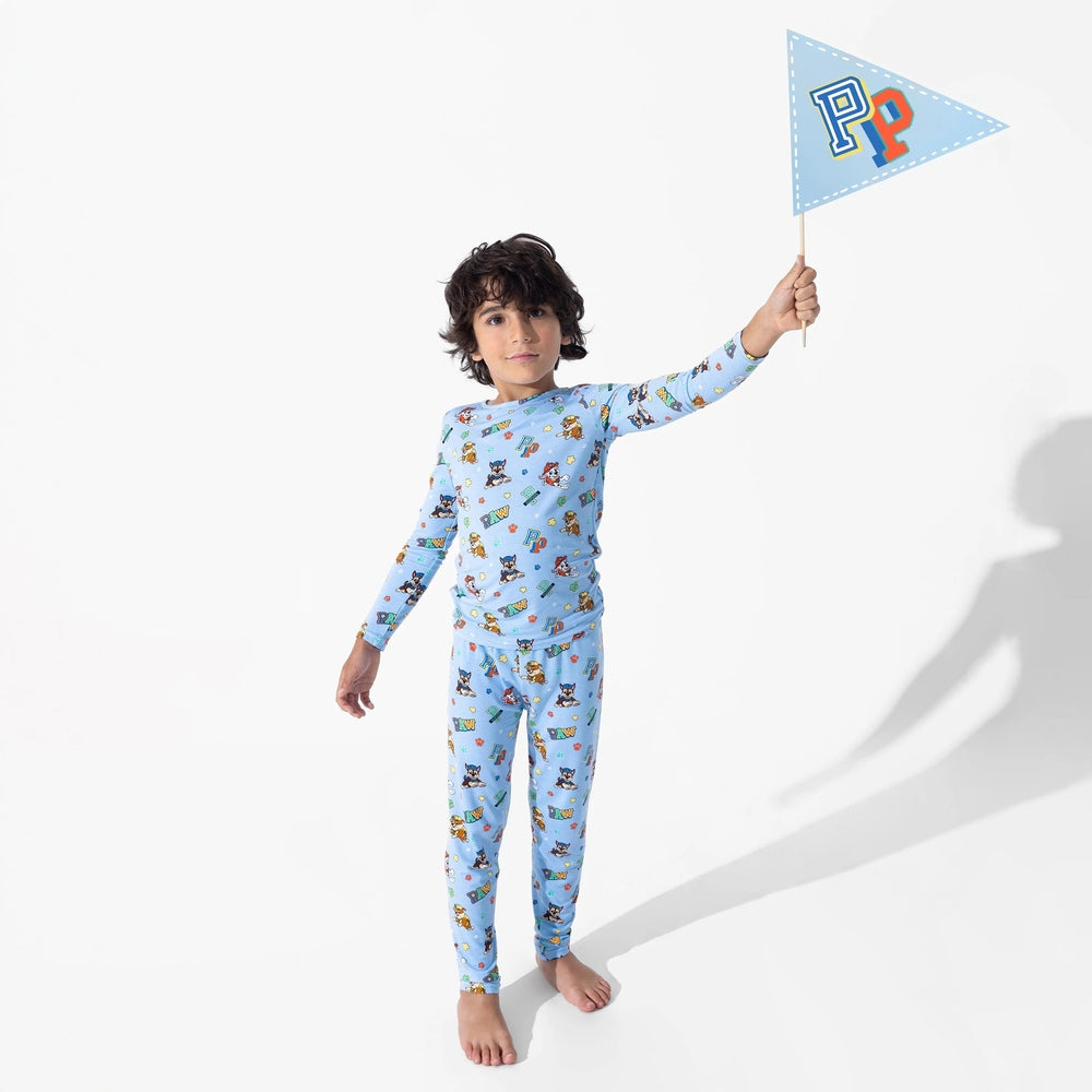 Bellabu Bear Varsity Blue Bamboo Kids Pajamas Paw Patrol, kid wearing blue printed PJs and waving a flag.