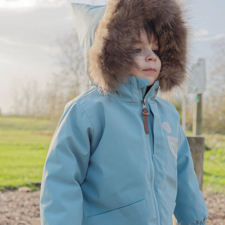 Boxbo Wistiti Fleece Lined Waterproof & Snowproof Fur Jacket Blue worn by a child outdoors in a fur-trimmed hood.