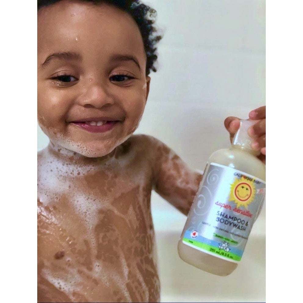 California Baby Super Sensitive No Fragrance Shampoo & Body Wash bottle held by smiling toddler during bath