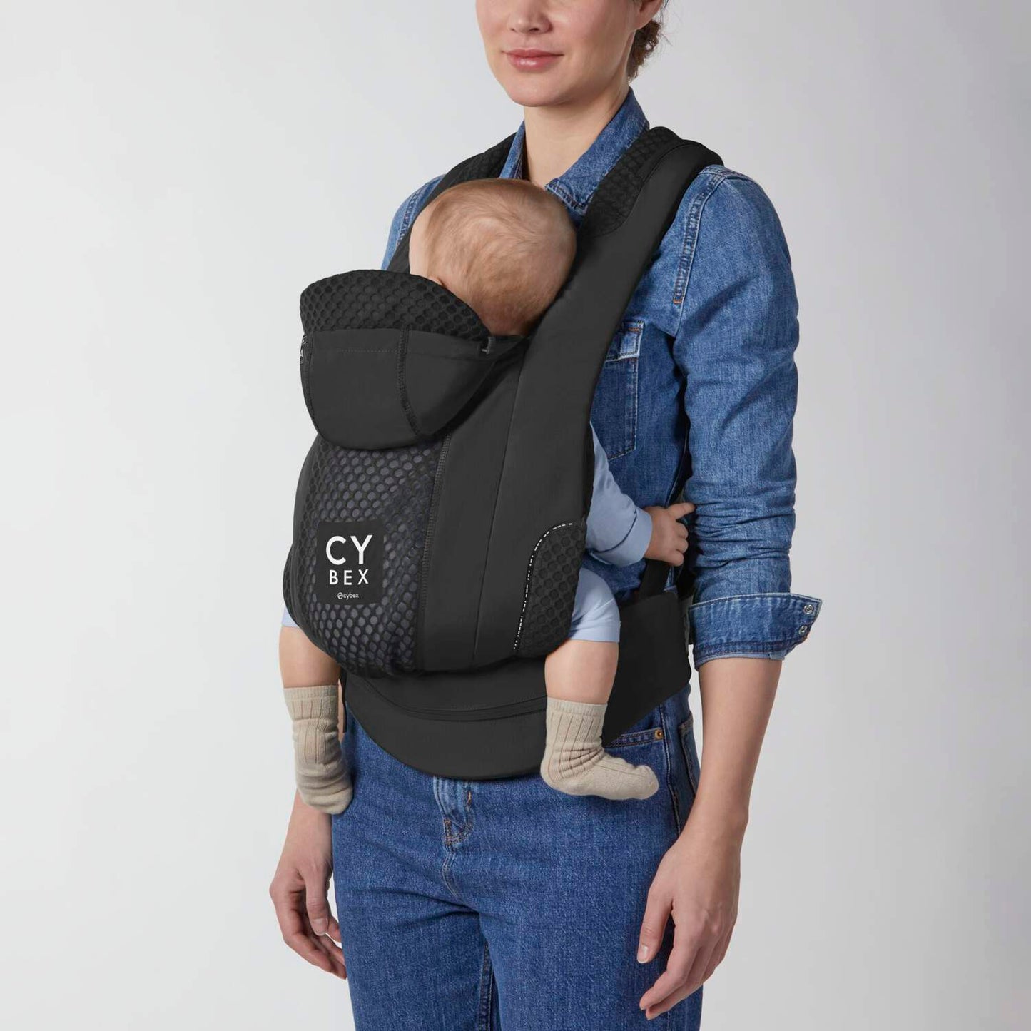 Cybex Coya Carrier in black with infant nestled inside; breathable mesh panels and padded straps