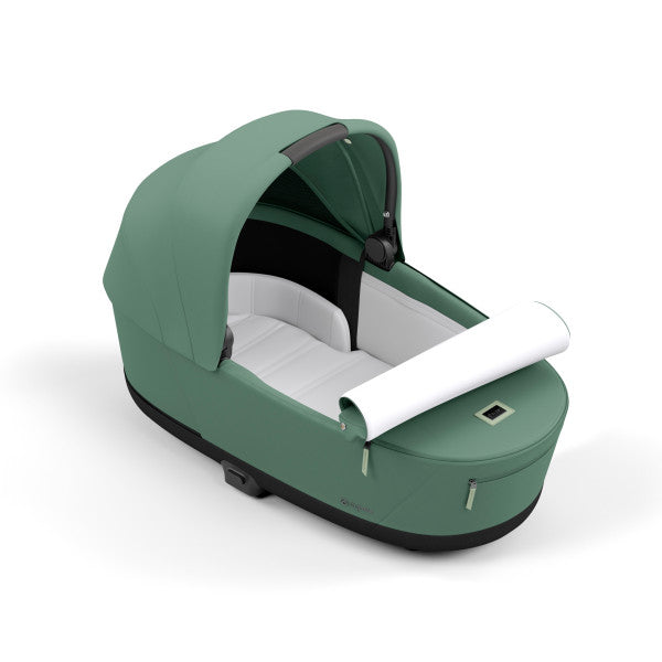 Cybex Priam Lux Carry Cot in green with white interior, sun canopy, and carry handle.