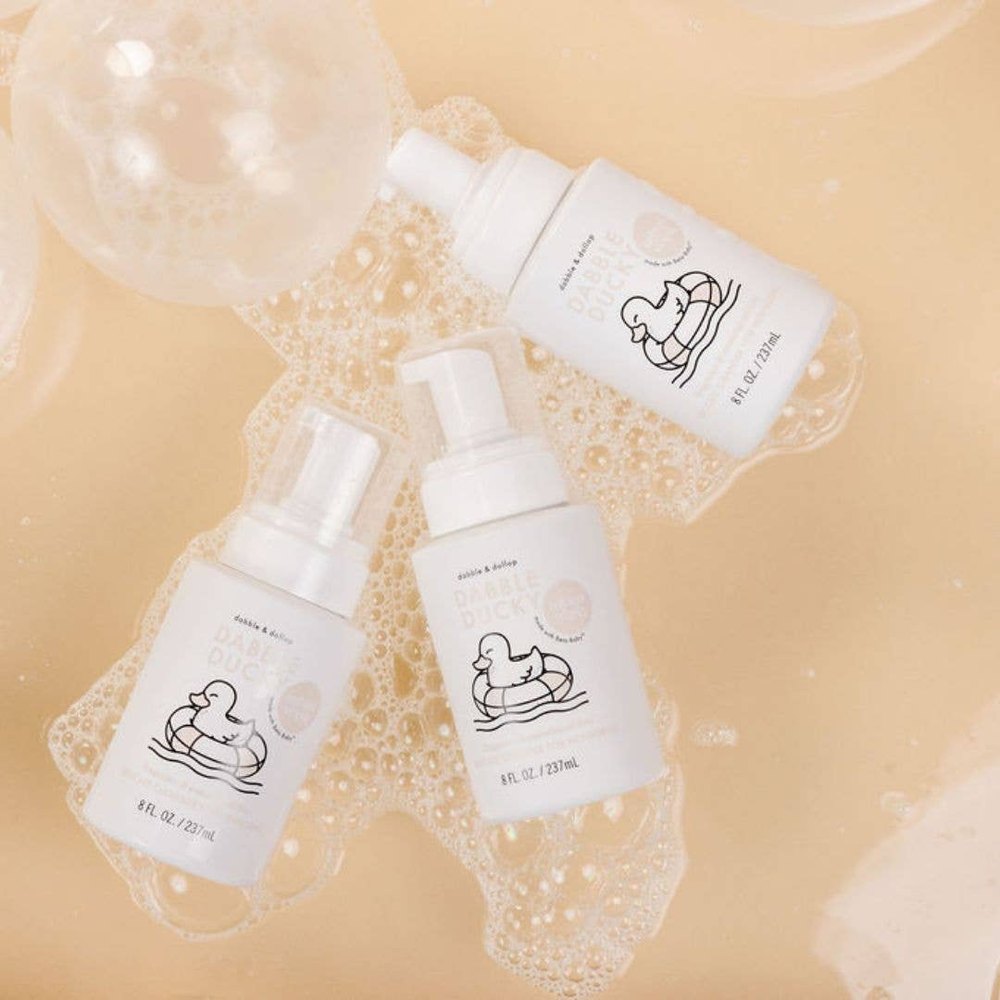 Dabble & Dollop All-Natural Infant Wash fragrance-free bottles with duck logo, surrounded by bubbly wash.