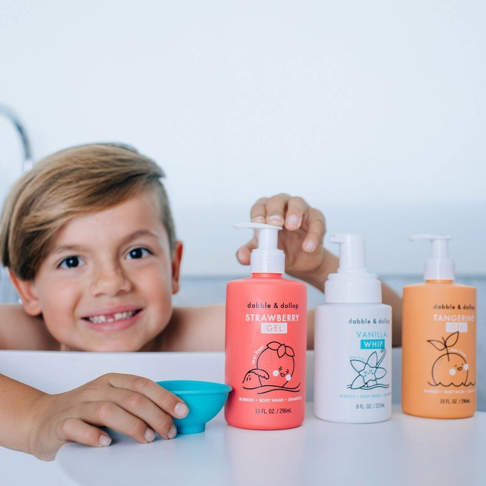 Dabble & Dollop All-Natural Shampoo, Body Wash & Bubbles Strawberry bottle pumped by a smiling child beside colorful bottles.