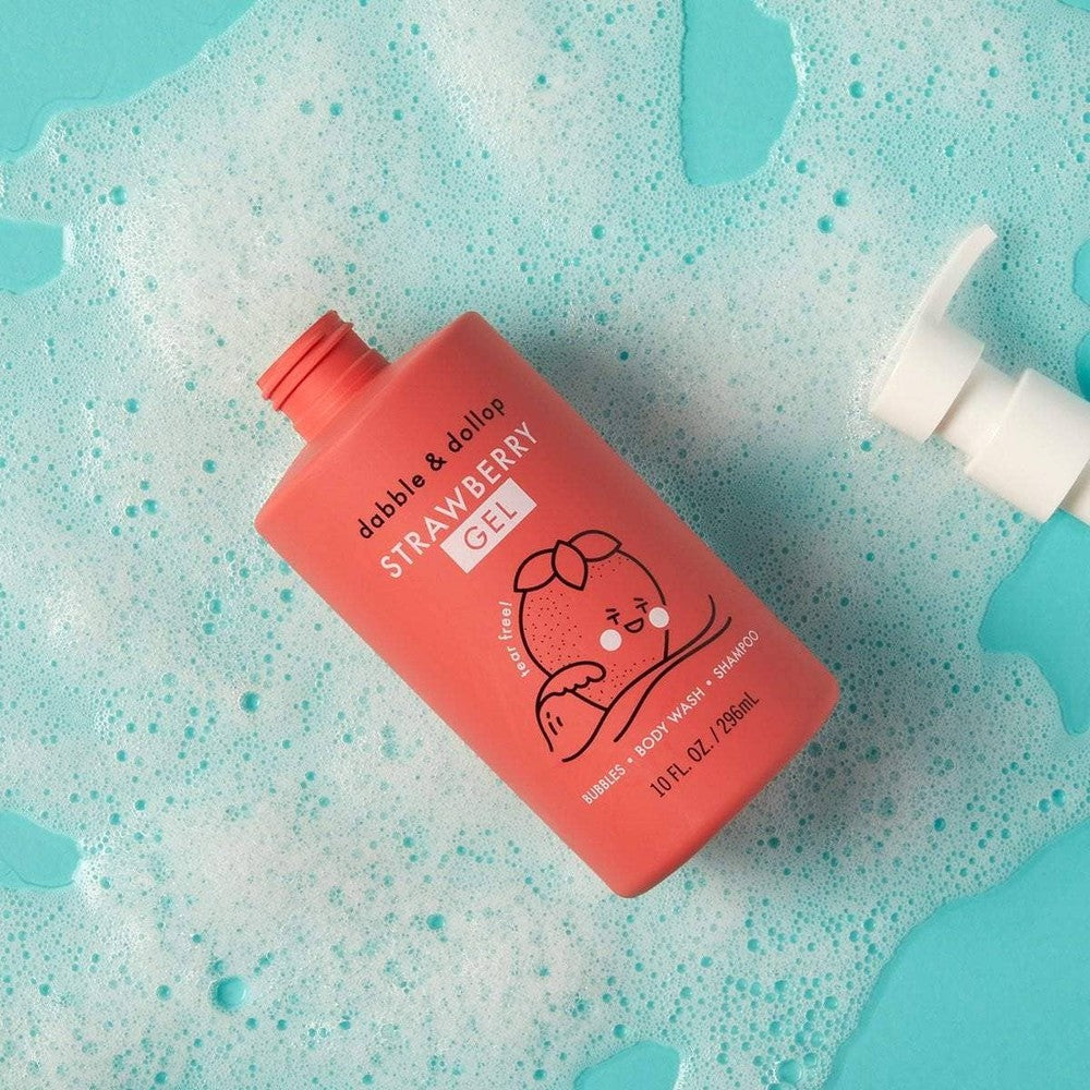 Dabble & Dollop All-Natural Shampoo, Body Wash & Bubbles Strawberry bottle resting on turquoise foamy bath.