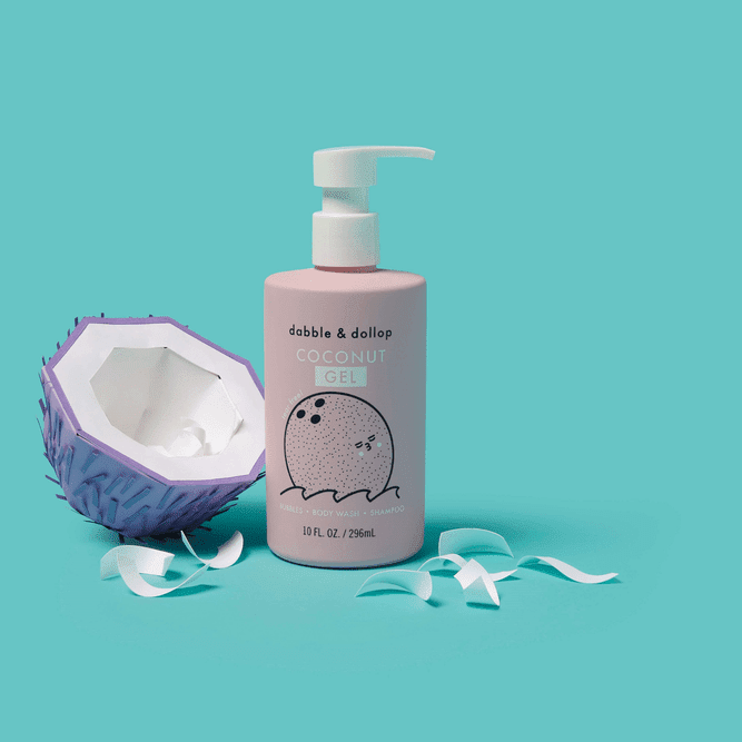 Dabble & Dollop All-Natural Shampoo, Body Wash & Bubbles Coconut pink pump bottle dispenses gel beside a halved purple coconut.
