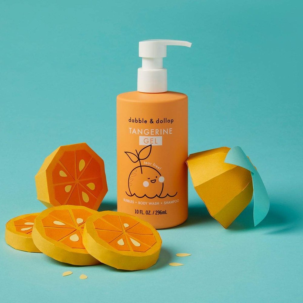 Dabble & Dollop Tangerine All-Natural Shampoo, Body Wash & Bubbles bottle with orange slices on teal backdrop